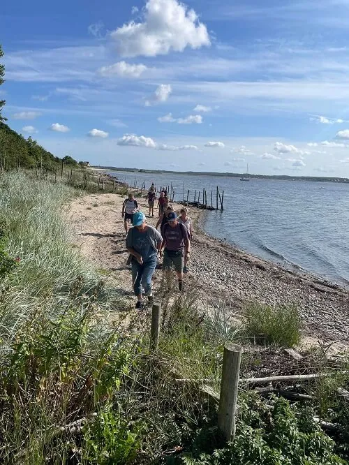 Gasten wandelen langs het strand aan de Limfjord