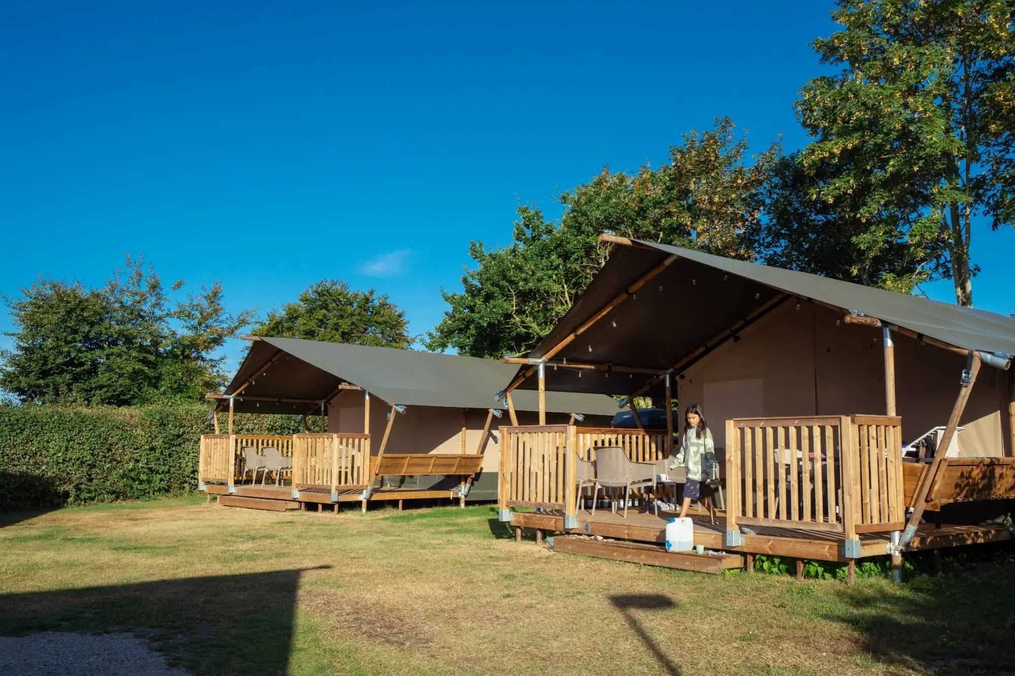 Glamping safaritenten met houten terras in de avondzon op Hvalpsund Familie Camping