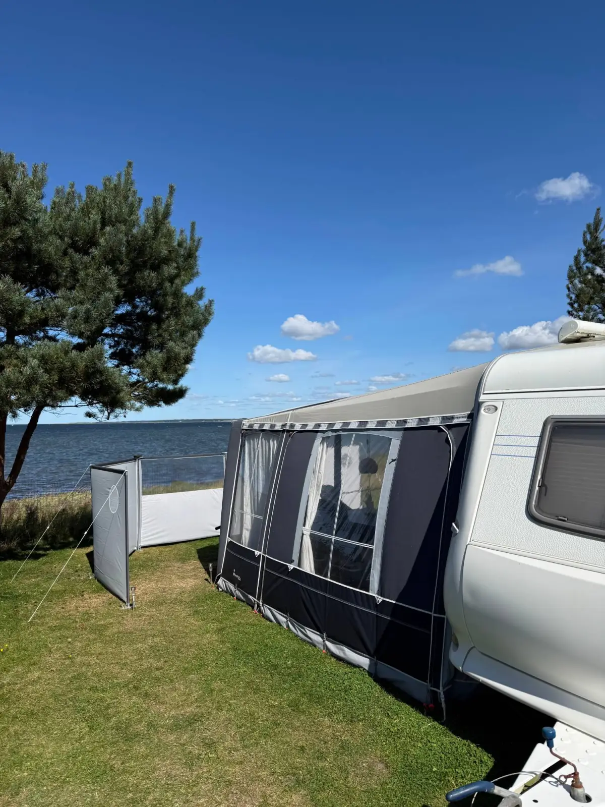 Caravan with awning and windbreak right by the fjord