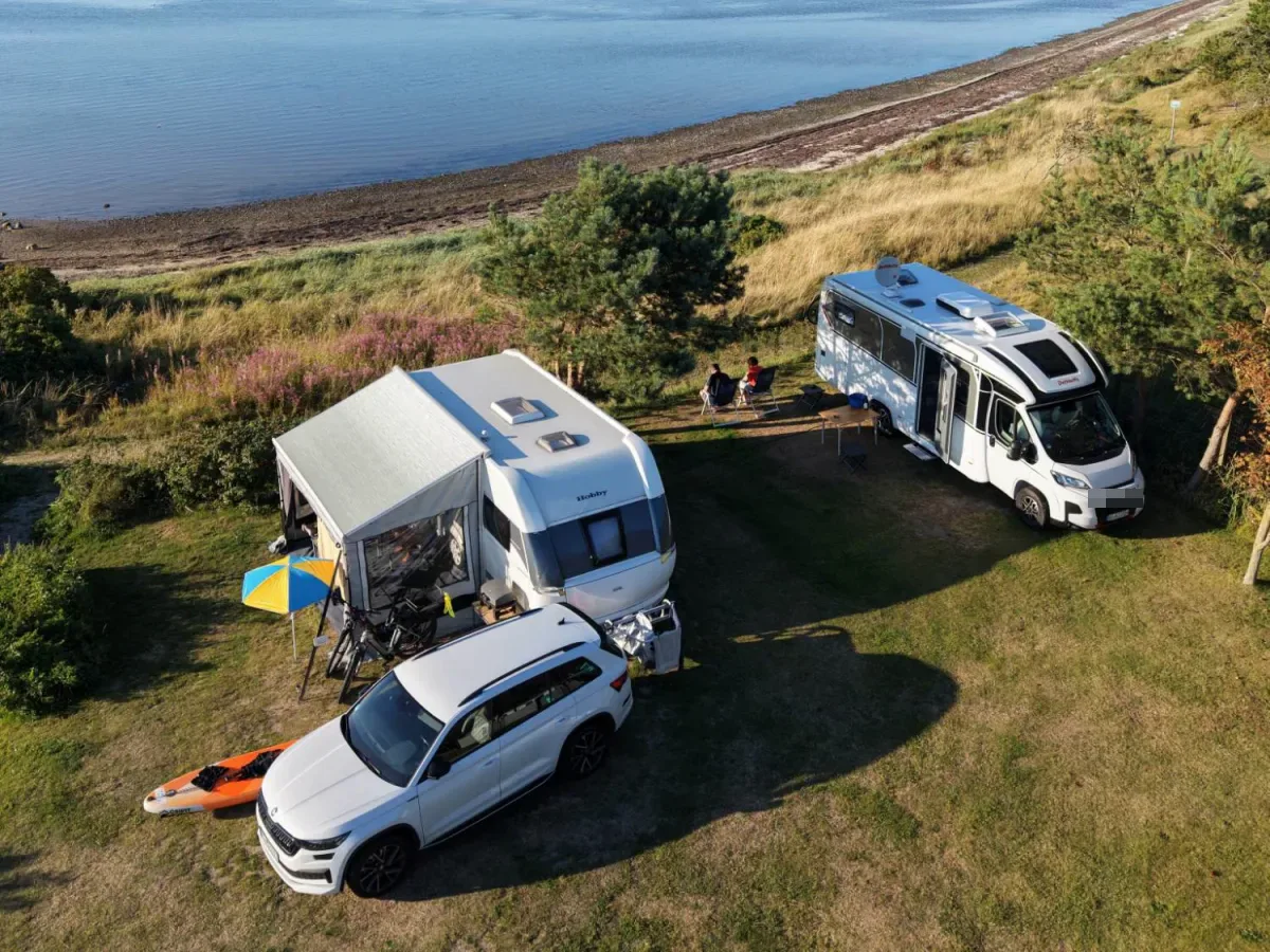 Caravan with awning and motorhome on panorama pitches just above the beach, seen from above