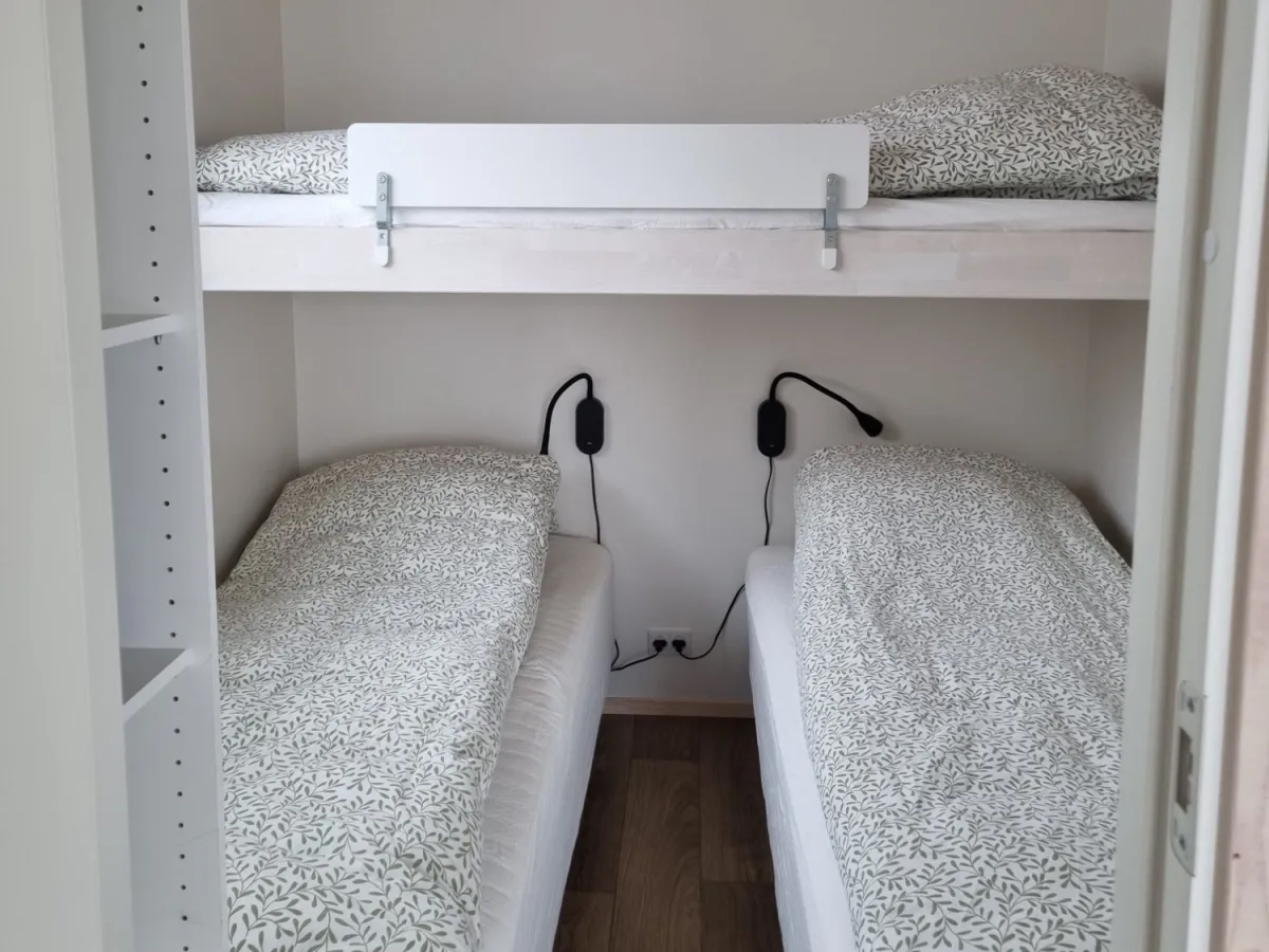 Slaapkamer met twee eenpersoonsbedden en een hoogslaper met bedhekje