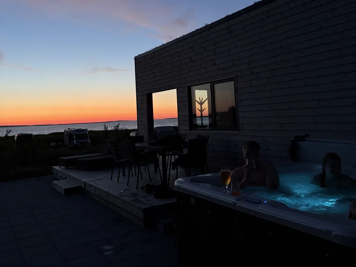 Gasten in de verlichte spa bij het huisje na zonsondergang