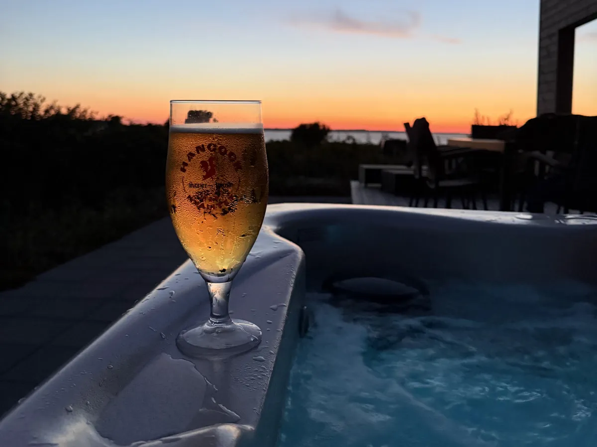 Een glas op de rand van de spa met zonsondergang boven de fjord