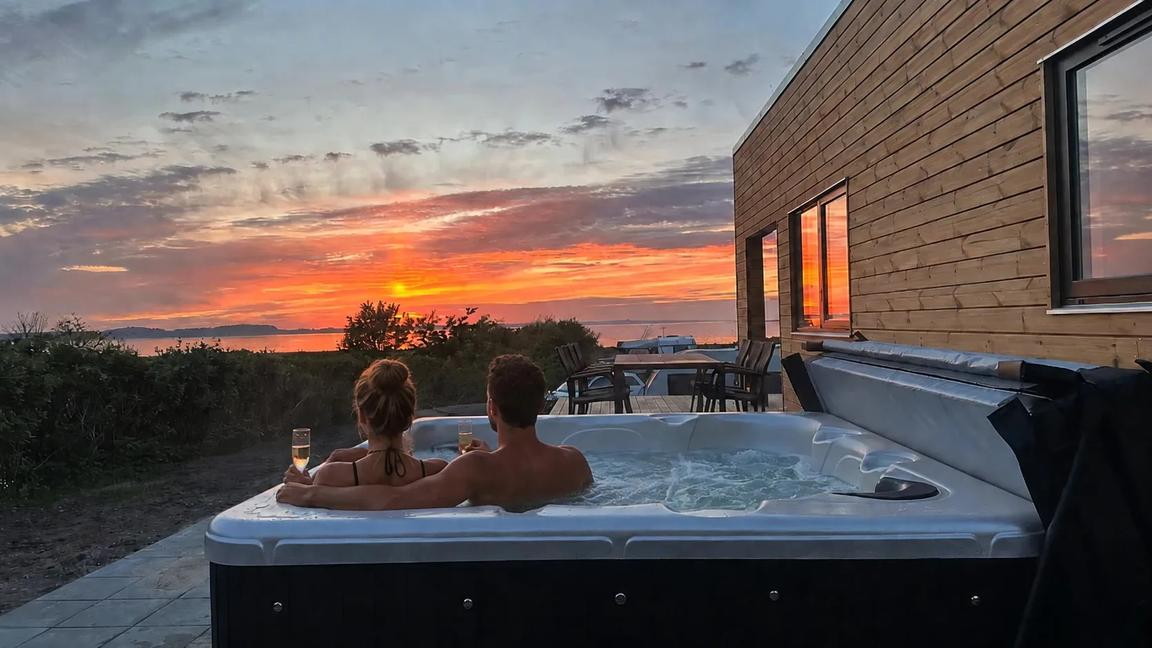 Par i den udendørs spa ved Premium Limfjordshytten med solnedgang over Limfjorden