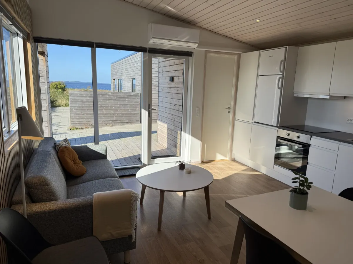 Lichte woonkamer en keuken met uitgang naar het terras en uitzicht op de fjord
