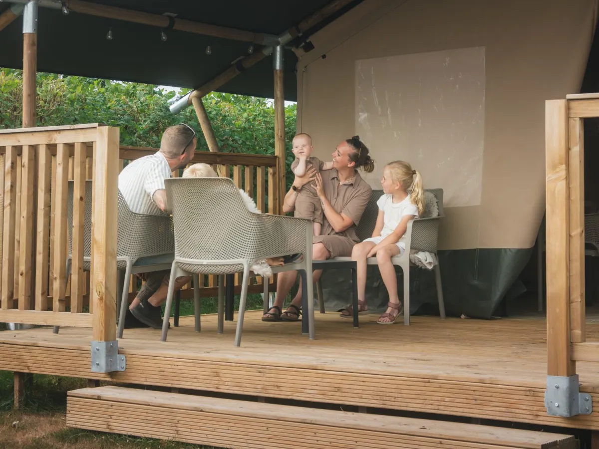 Gezin ontspant op het overdekte terras voor de safaritent