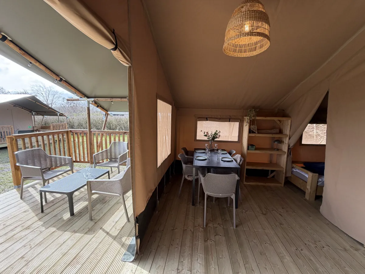 Doorkijk in de safaritent van de slaapruimte naar de eettafel en het terras