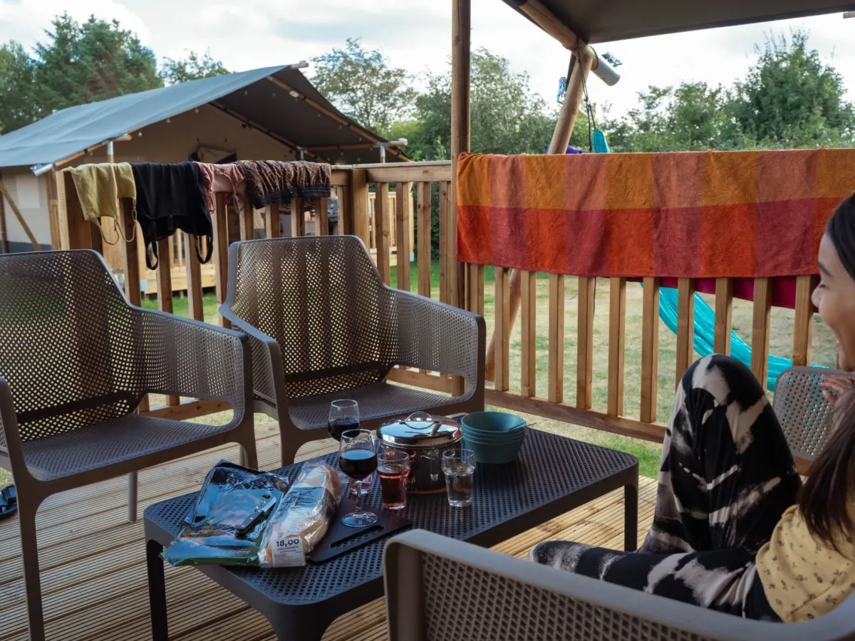 Loungemeubels op het terras van de safaritent met avondeten op tafel