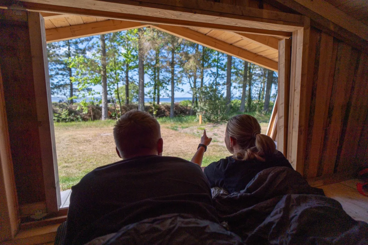 Par ligger i shelter og ser ud mod skov og Limfjord