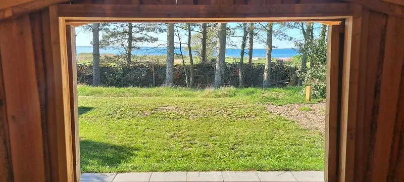 Uitzicht vanuit de shelter over het gras naar de fjord