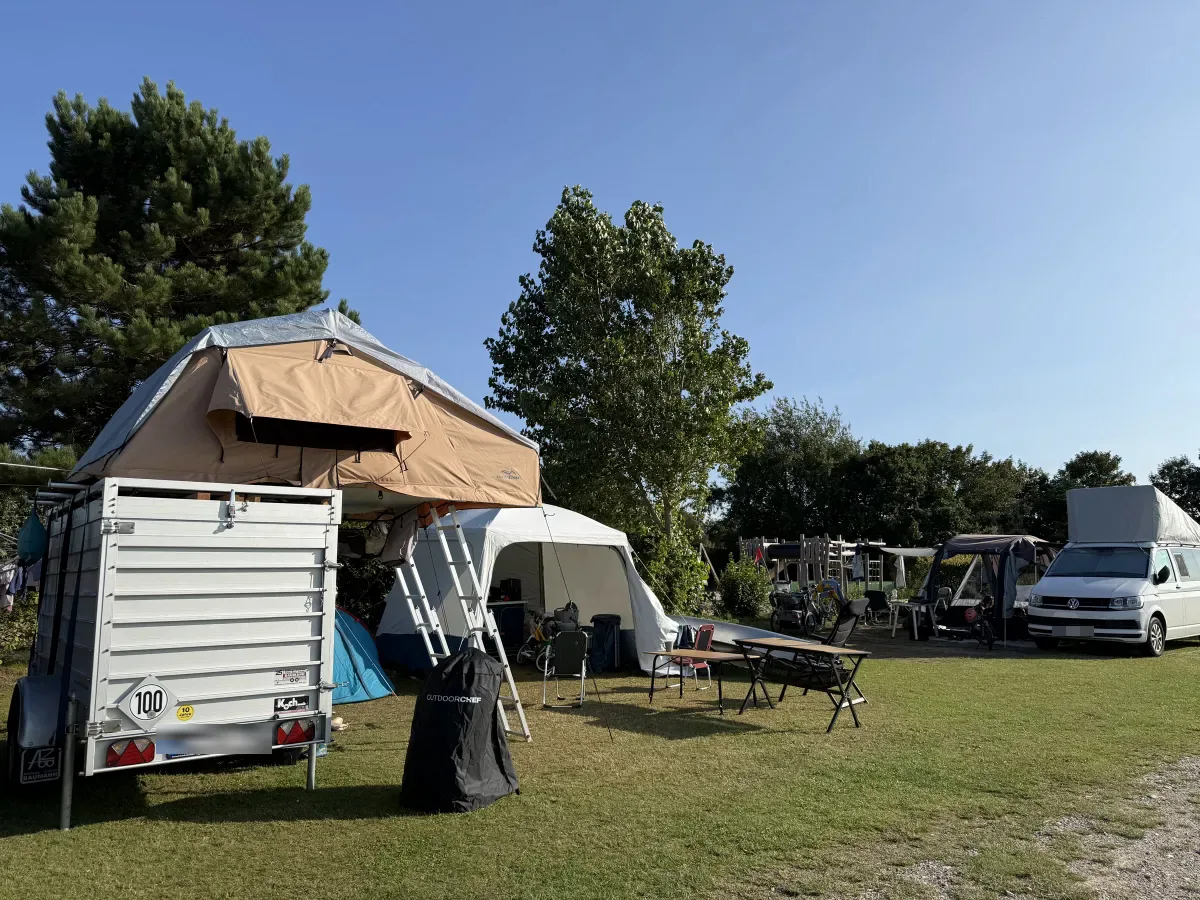 Standaardplaats met aanhanger, daktent en tent op een zonnige dag