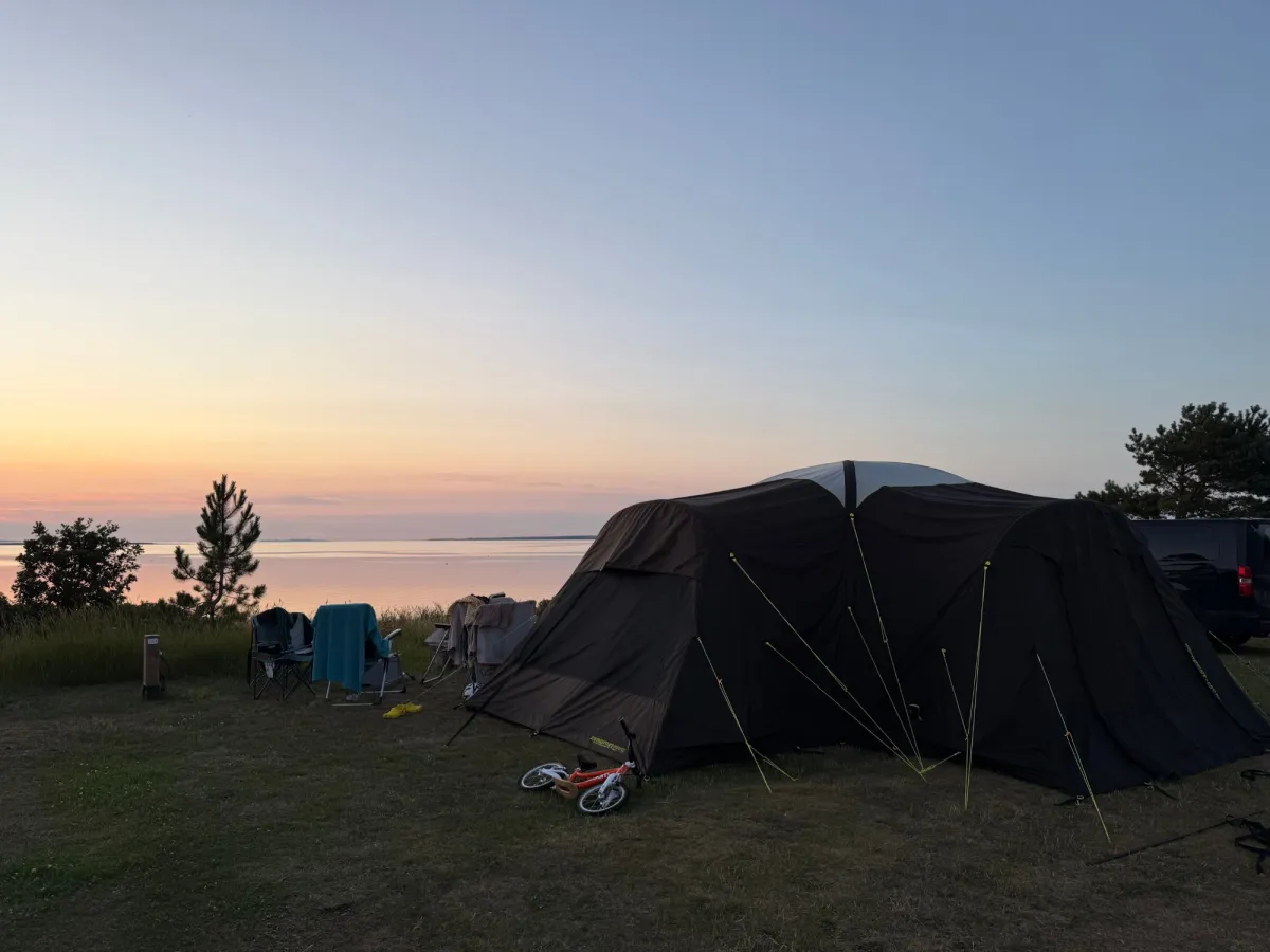 Grote tent en stoelen aan de fjord bij zonsondergang