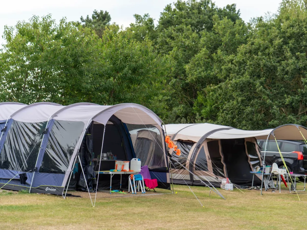 Grote familietenten met keukentafel onder de bomen