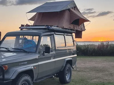 Daktent op een auto met zonsondergang boven de fjord