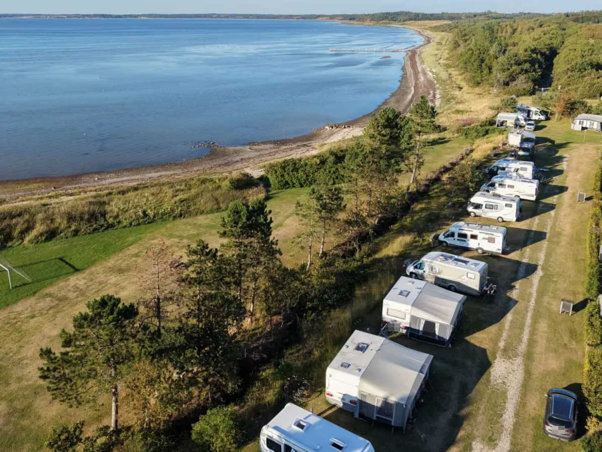 Caravans and motorhomes in a row along the coast with the Limfjord and the bathing jetty, seen from above