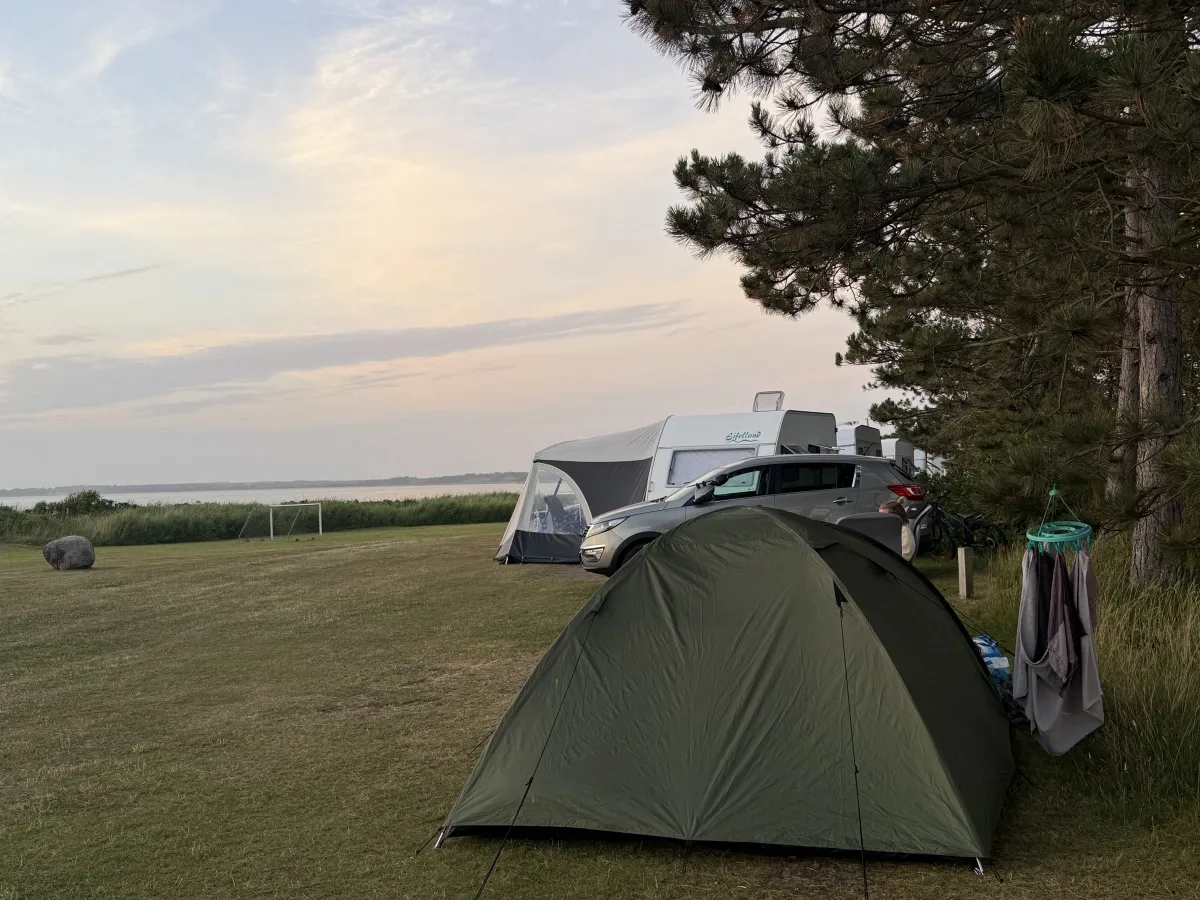 Tent, auto en caravan op een uitzichtplaats met de fjord in het avondlicht
