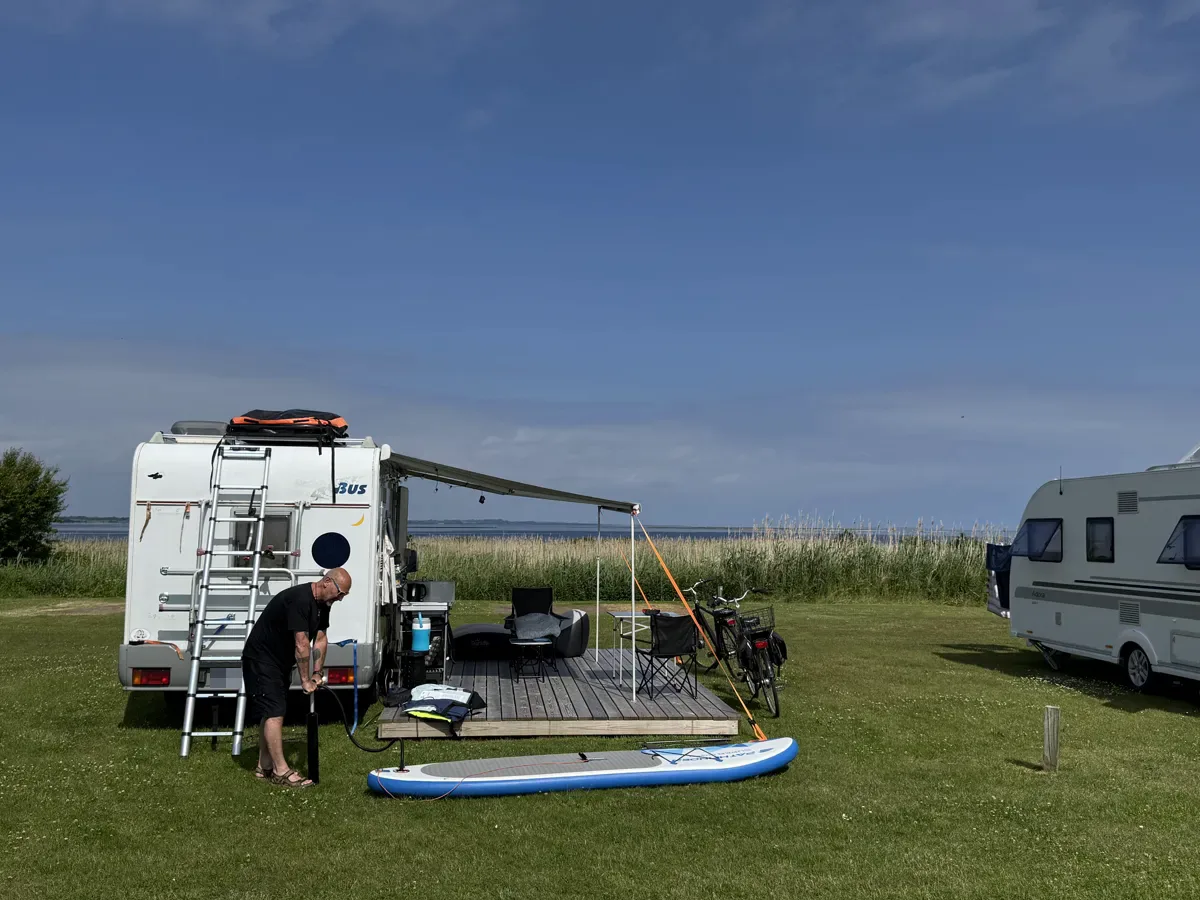 Motorhome with awning and SUP board on a view pitch with a wooden deck