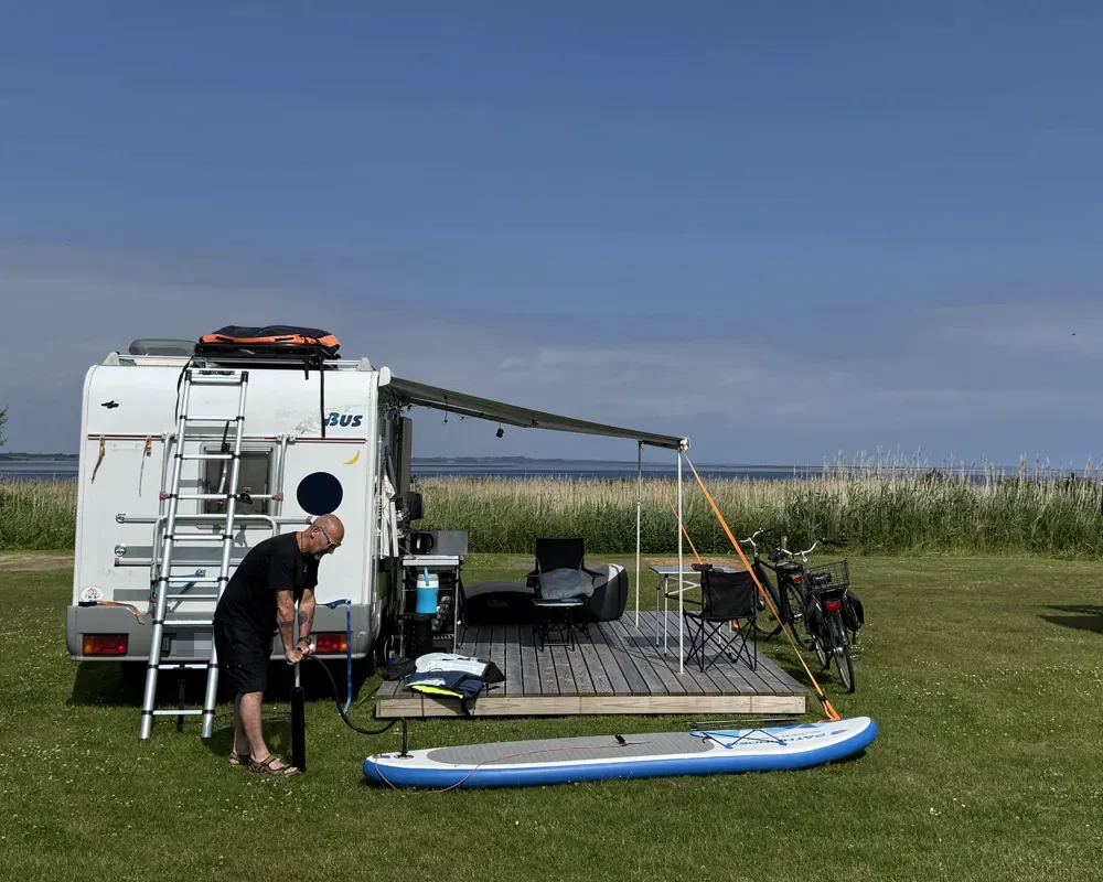 Camper op een plaats met uitzicht en houten terras aan de Limfjord
